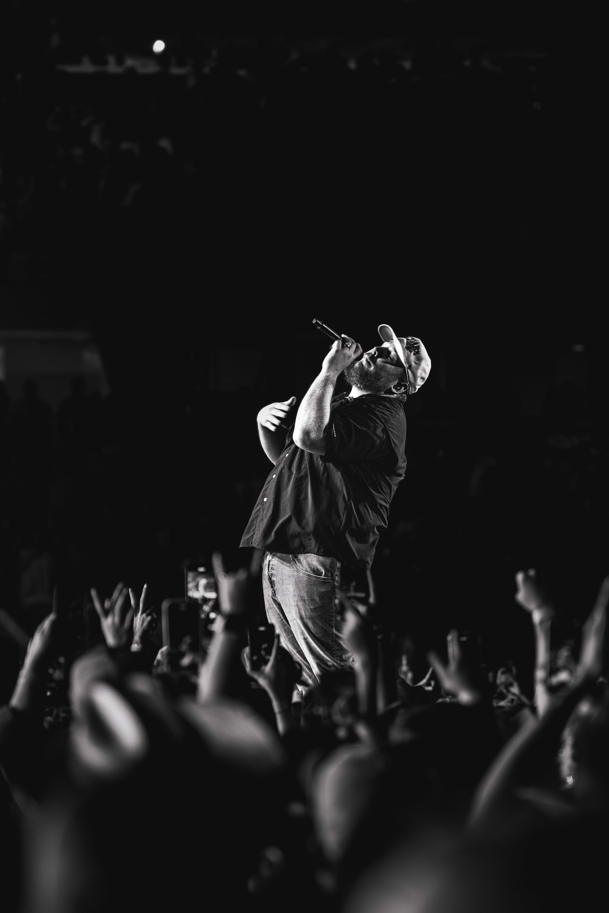 Luke Combs in black and white, singing over a floor of raised hands.