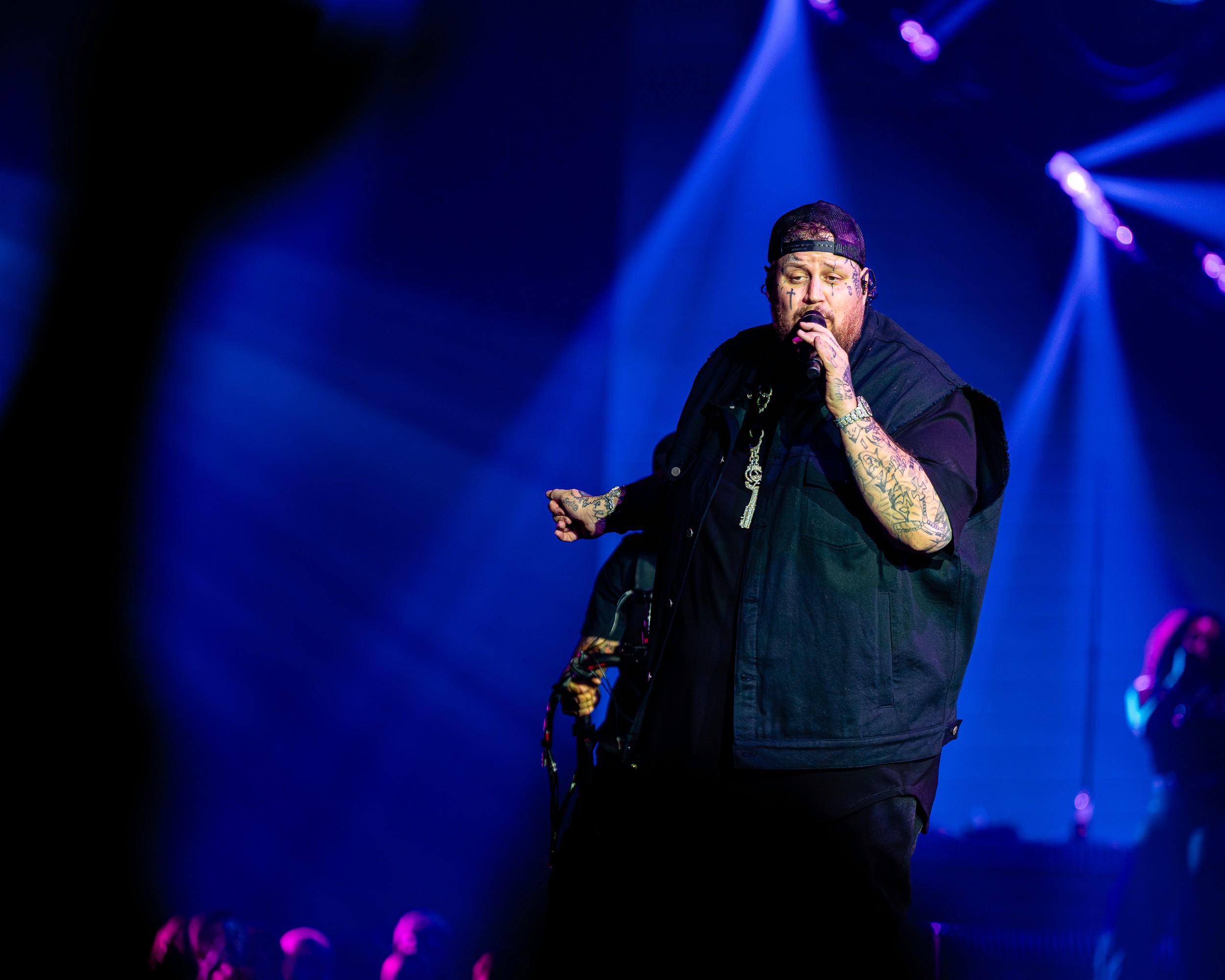 Jelly Roll on the mic in blue light, a backing singer behind him.
