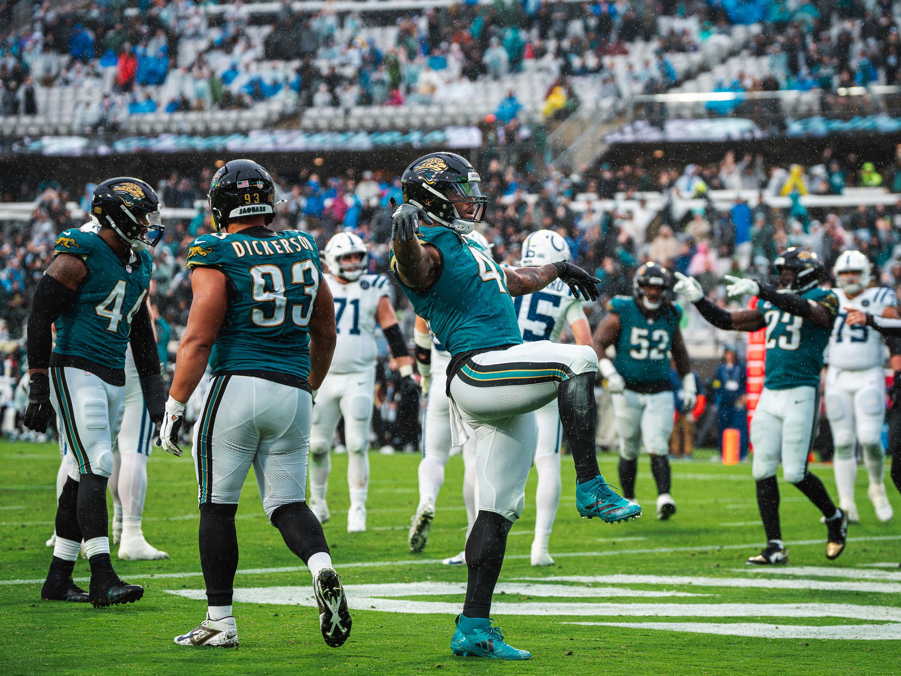 The Jaguars defense celebrates a stop with a high kick in the rain, DaVon Hamilton (52) behind the play.