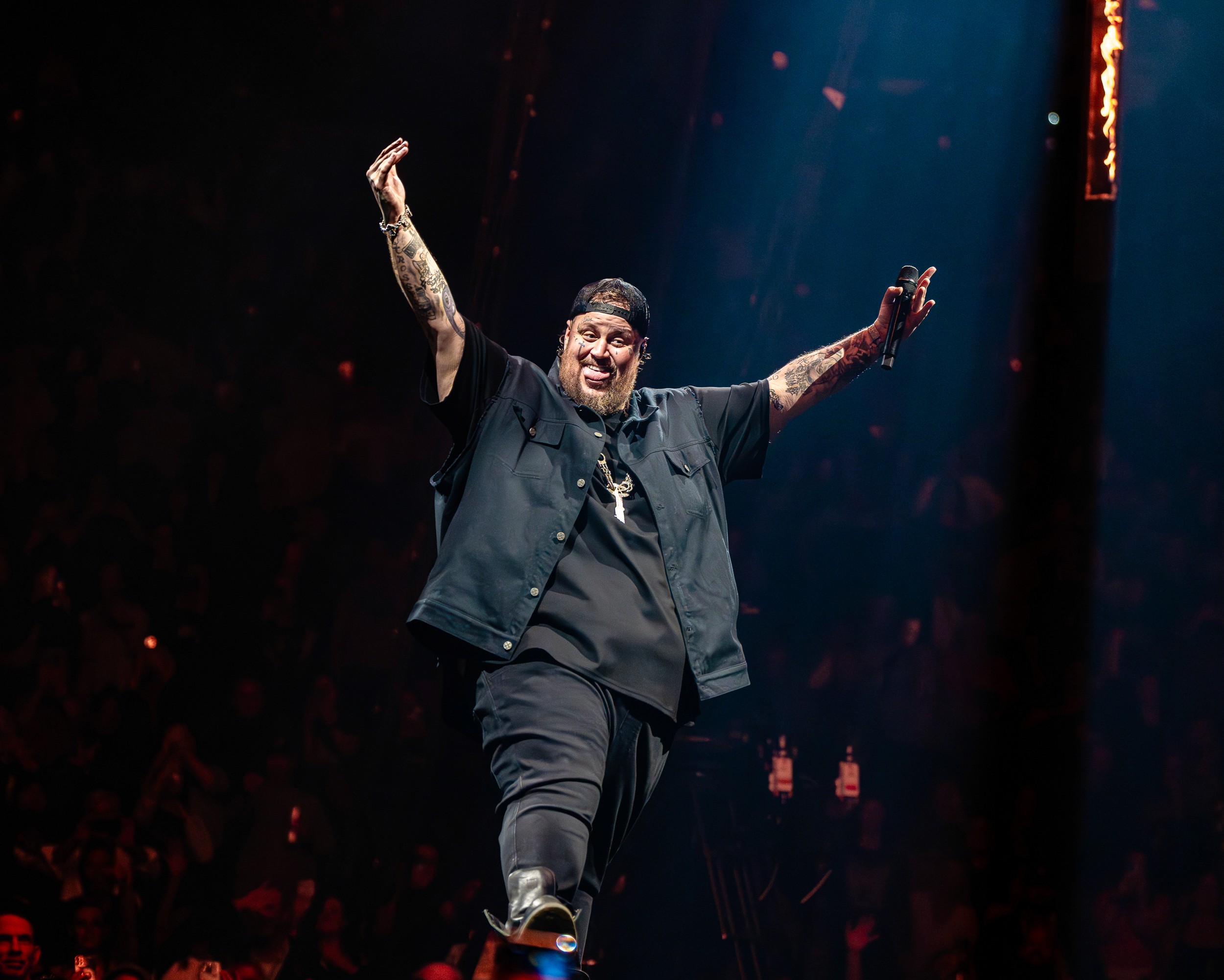Jelly Roll walks the runway with both arms up, flames on the rig behind him.