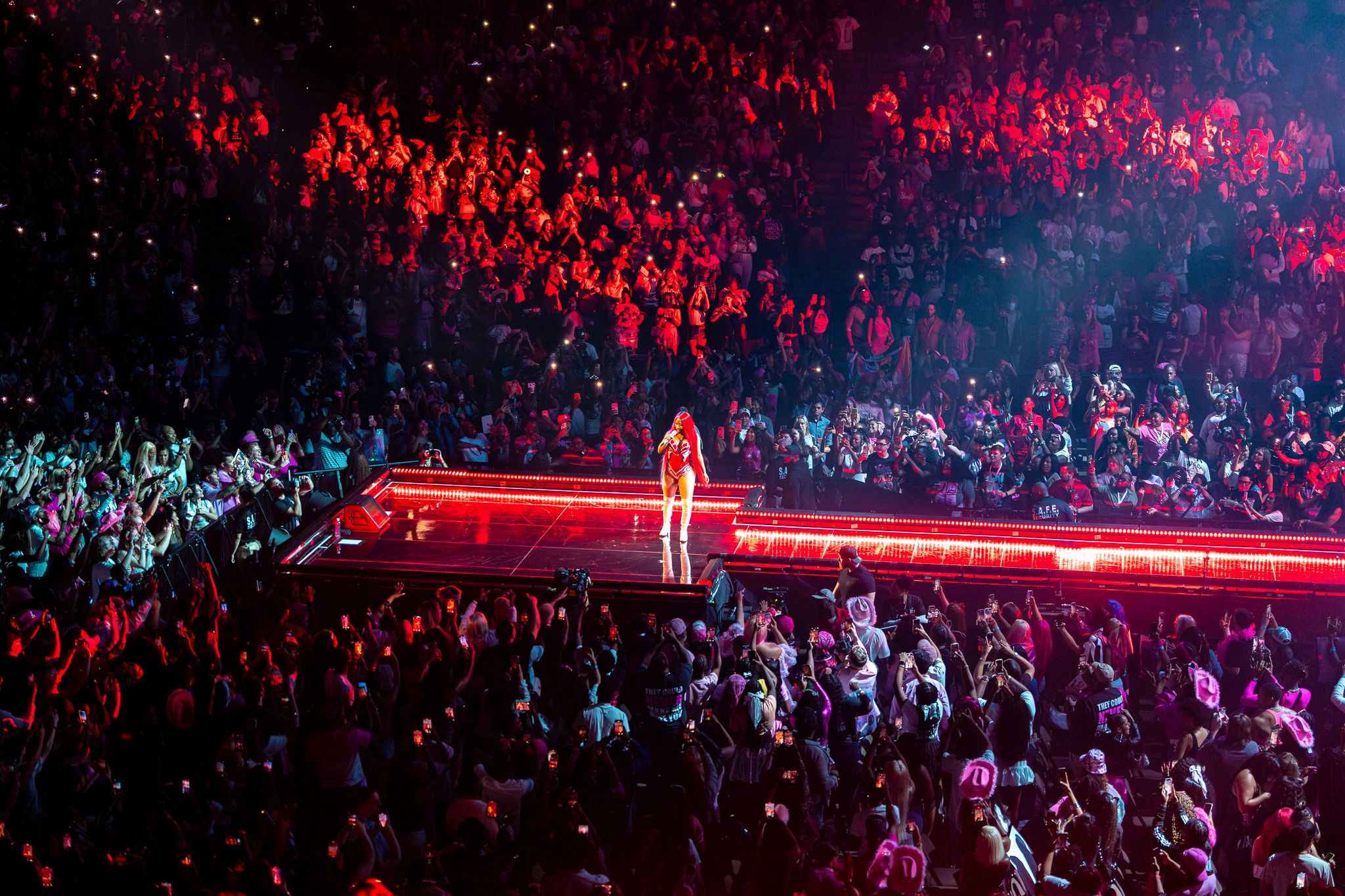 The whole floor from above: Nicki Minaj alone on the red-lit runway, the bowl behind her.