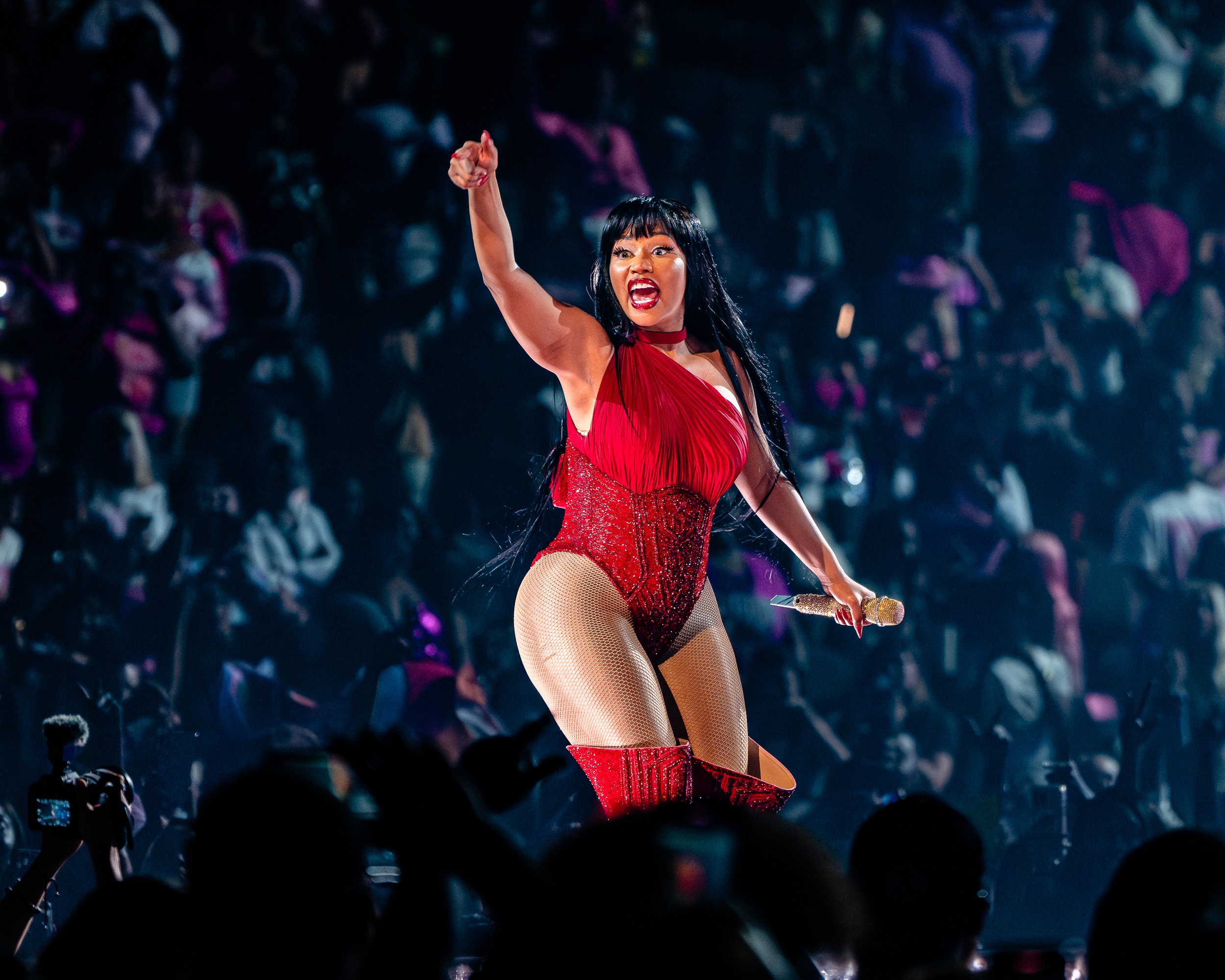 Nicki Minaj in red, fist raised, from the pit.
