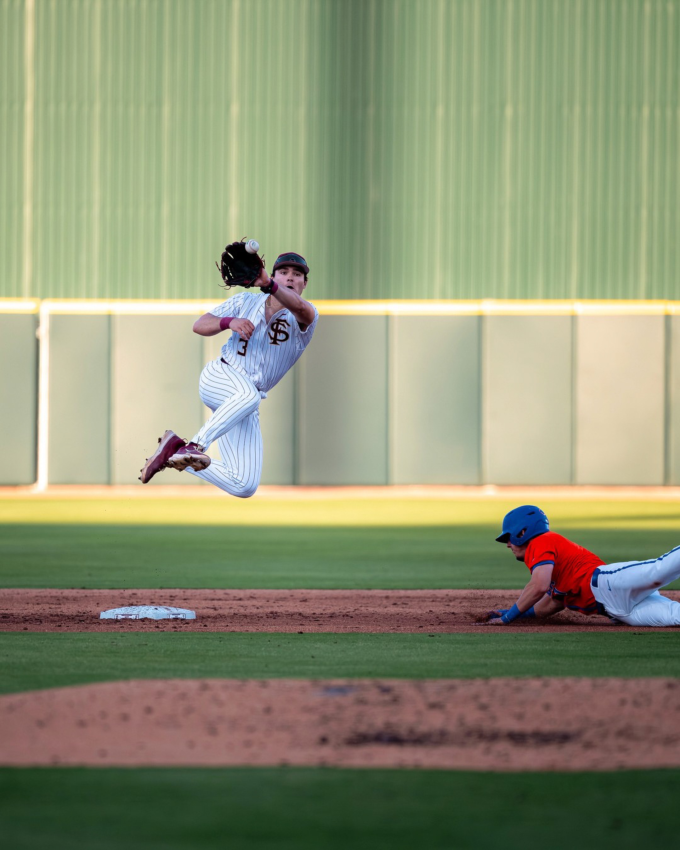 A Florida State infielder leaves his feet over the sliding Florida runner to complete the turn at second base.