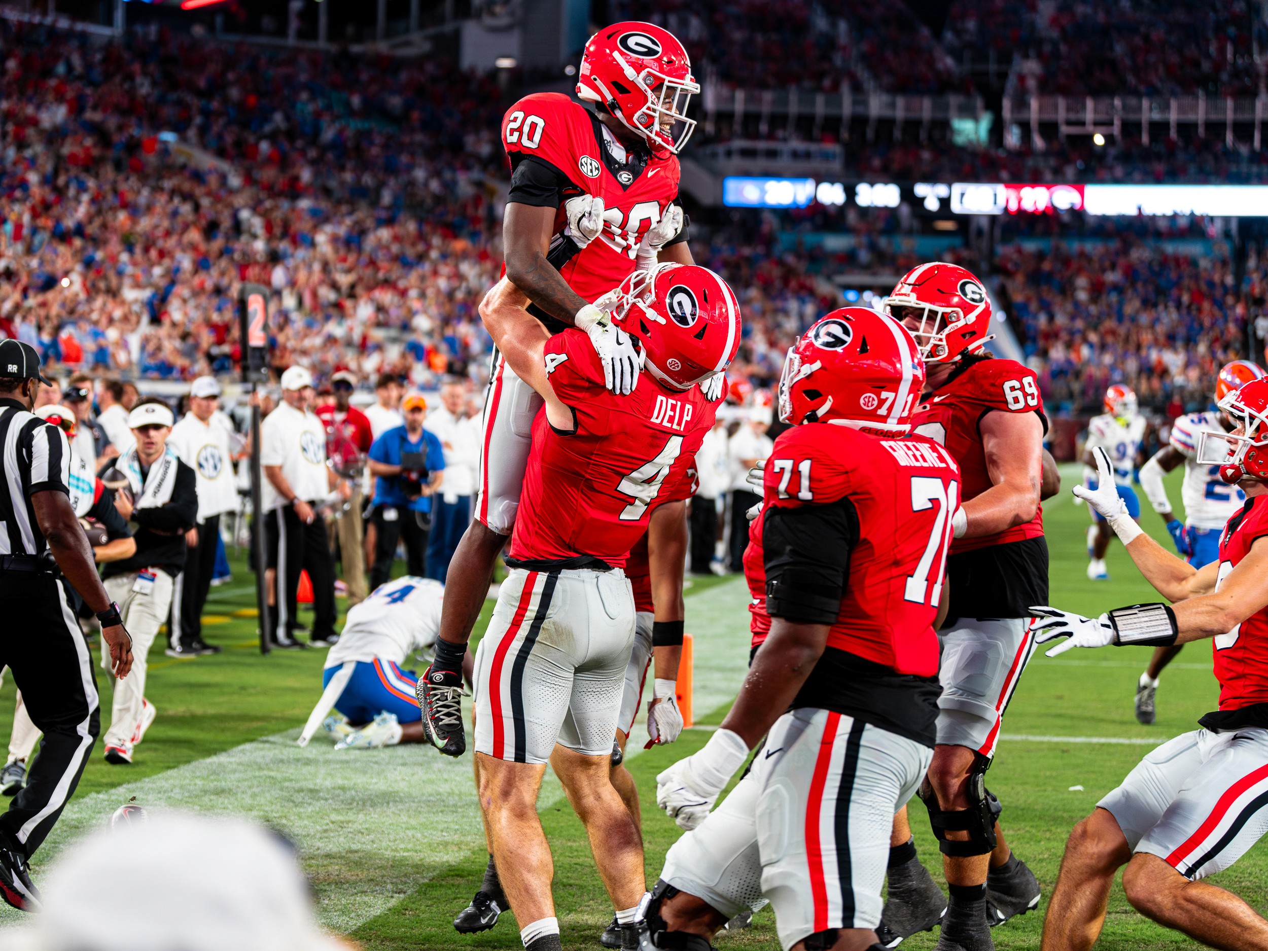 Georgia tight end Oscar Delp (4) lifts a teammate in the end zone after a score in front of the Florida sideline.