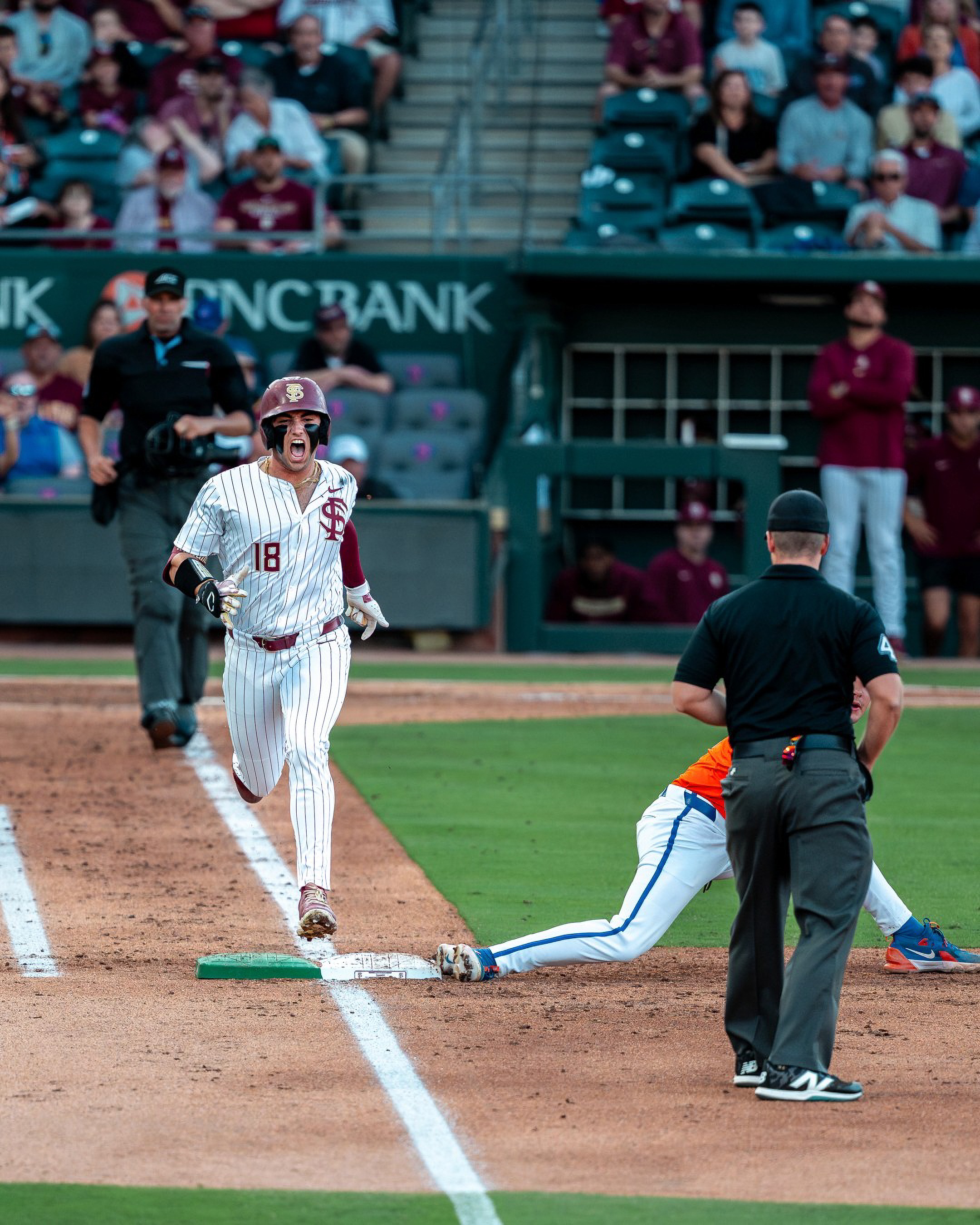 A Florida State runner beats the throw at first, the umpire watching Florida’s first baseman stretch for the ball.