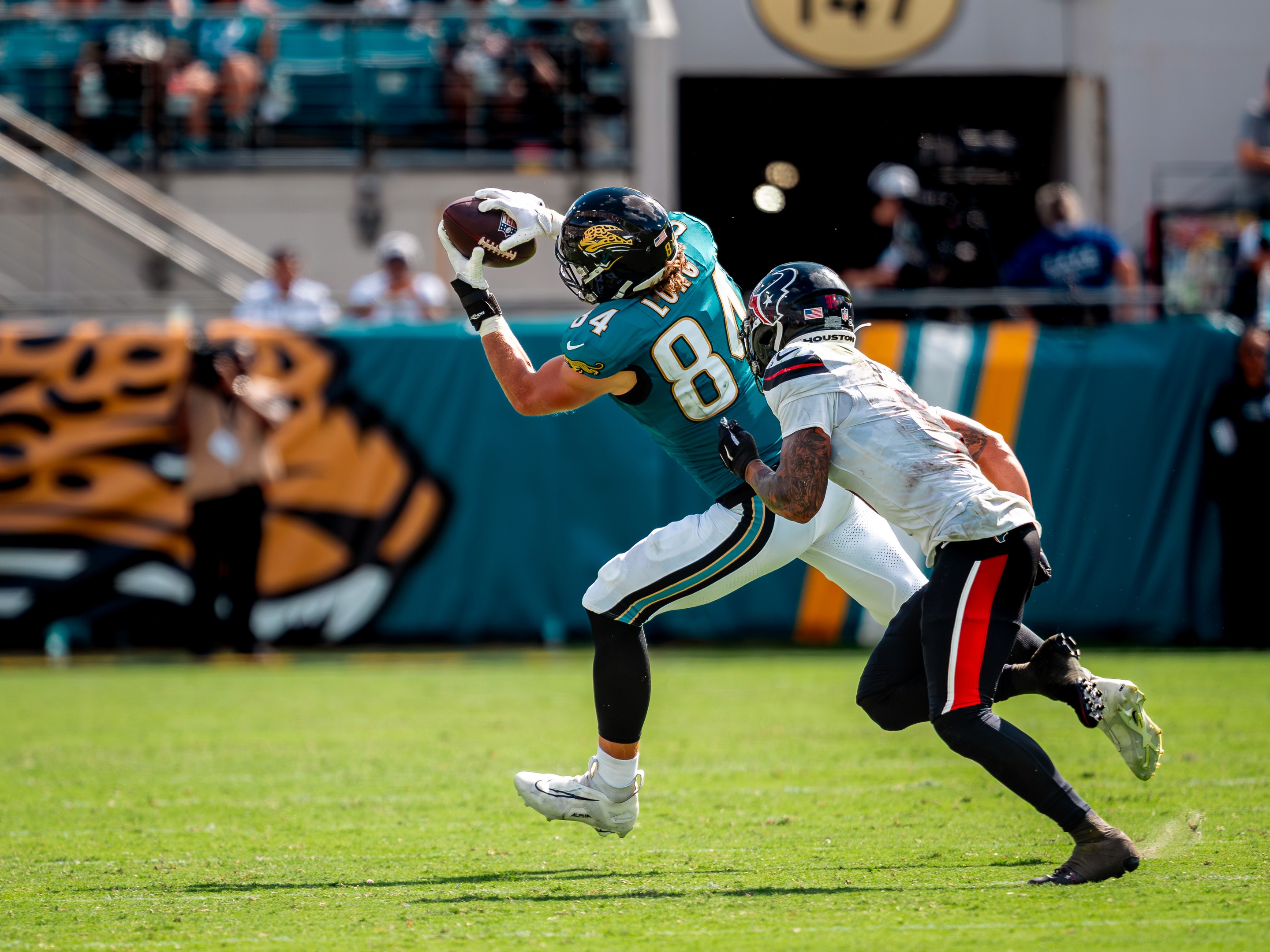 A Jaguars back turns the corner toward the pylon with the stands up behind him.