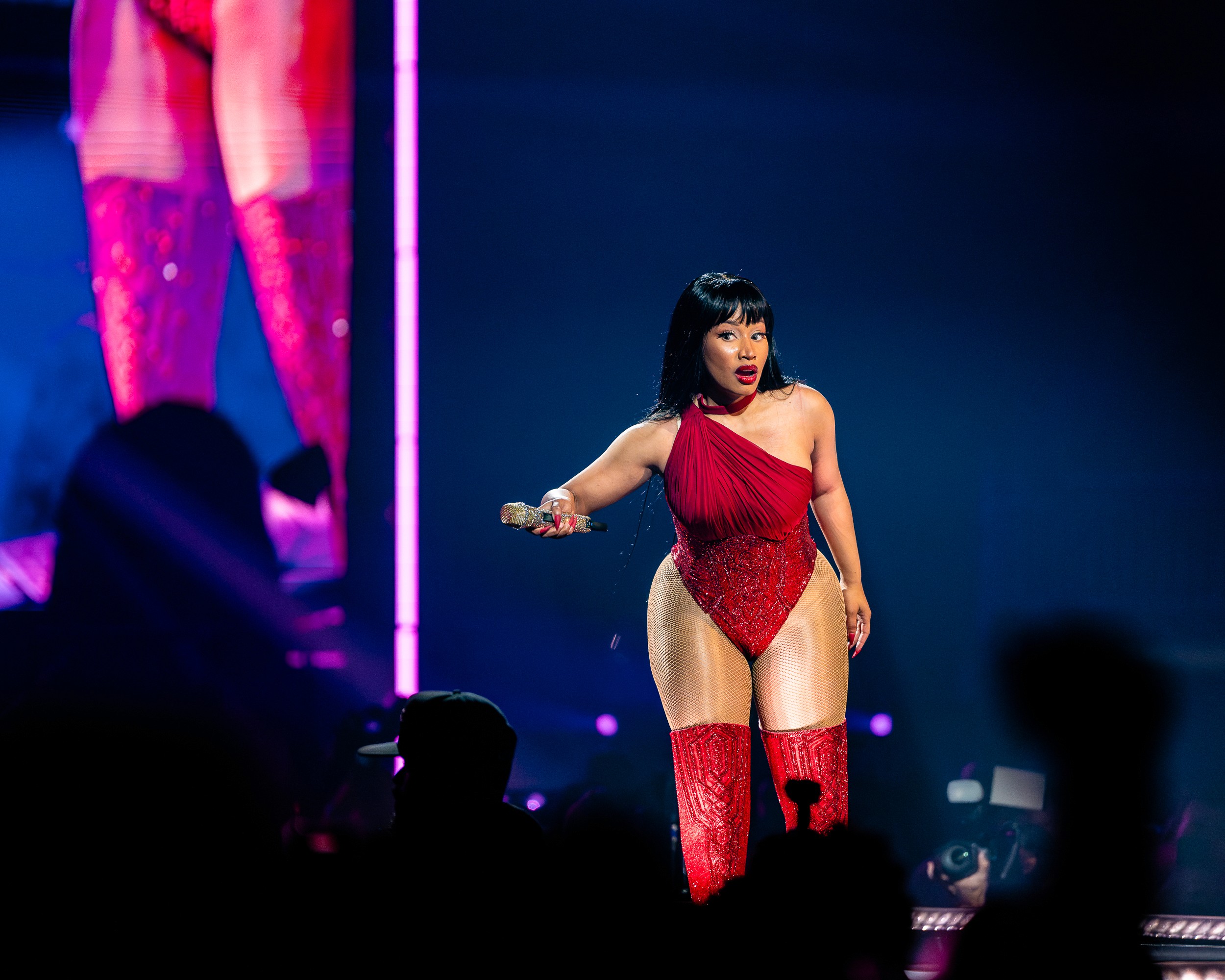Nicki Minaj in red on the runway, mic out to the crowd, her image on the screen.