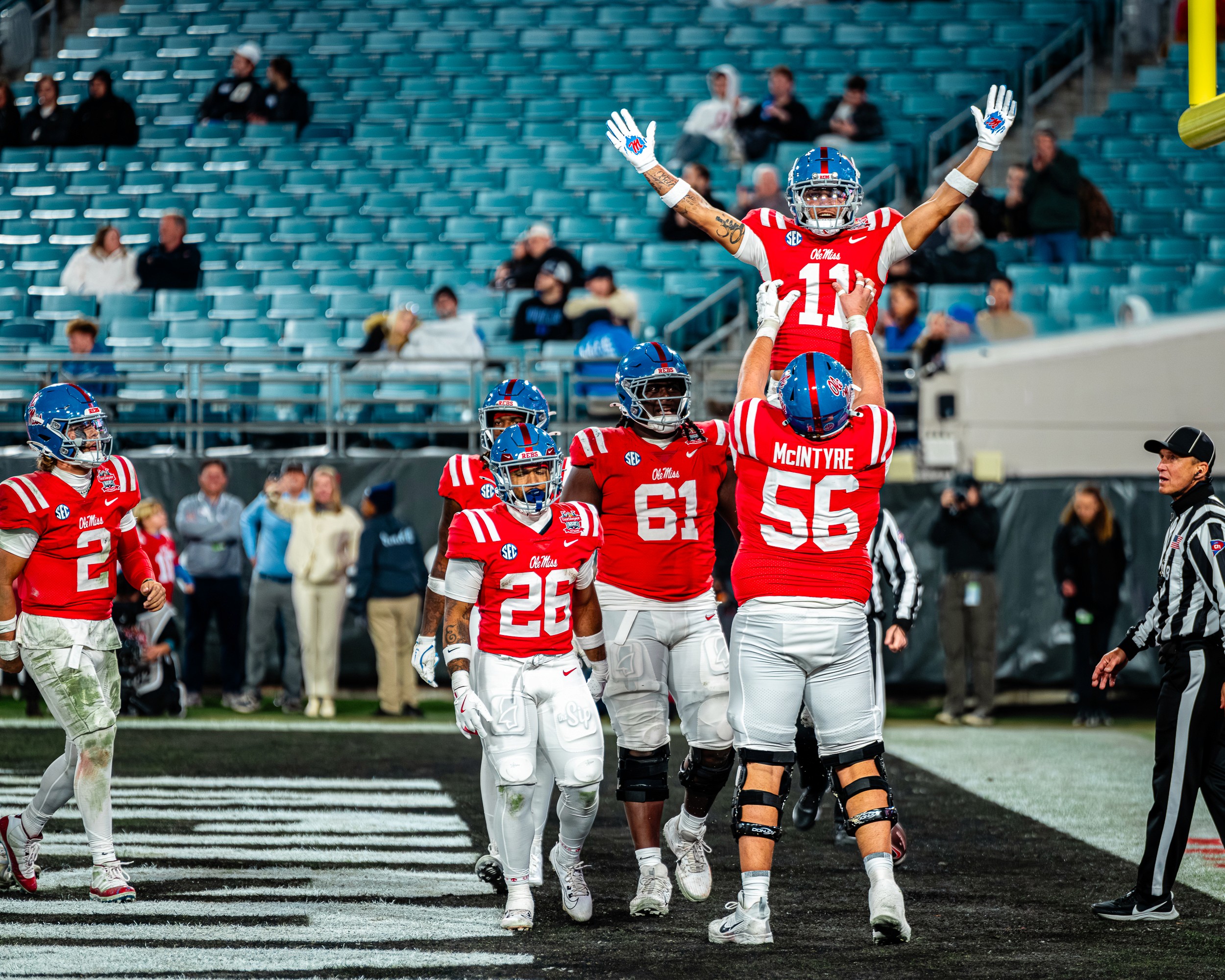 Lineman Reece McIntyre (56) lifts a teammate in the end zone, quarterback Jaxson Dart (2) coming to join.