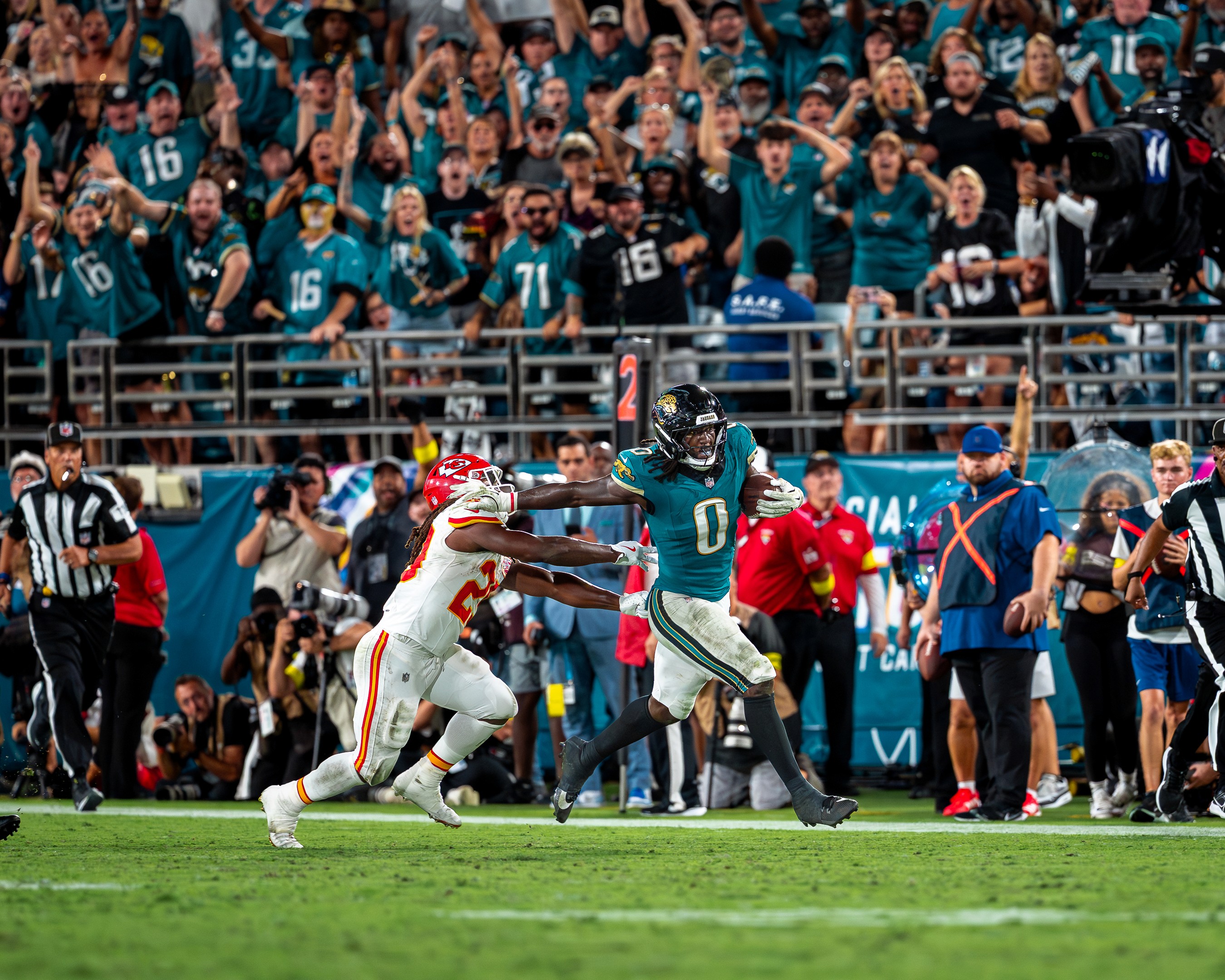 A Jaguars defender stiff-arms a Chiefs player on a return, the stands on their feet behind him.