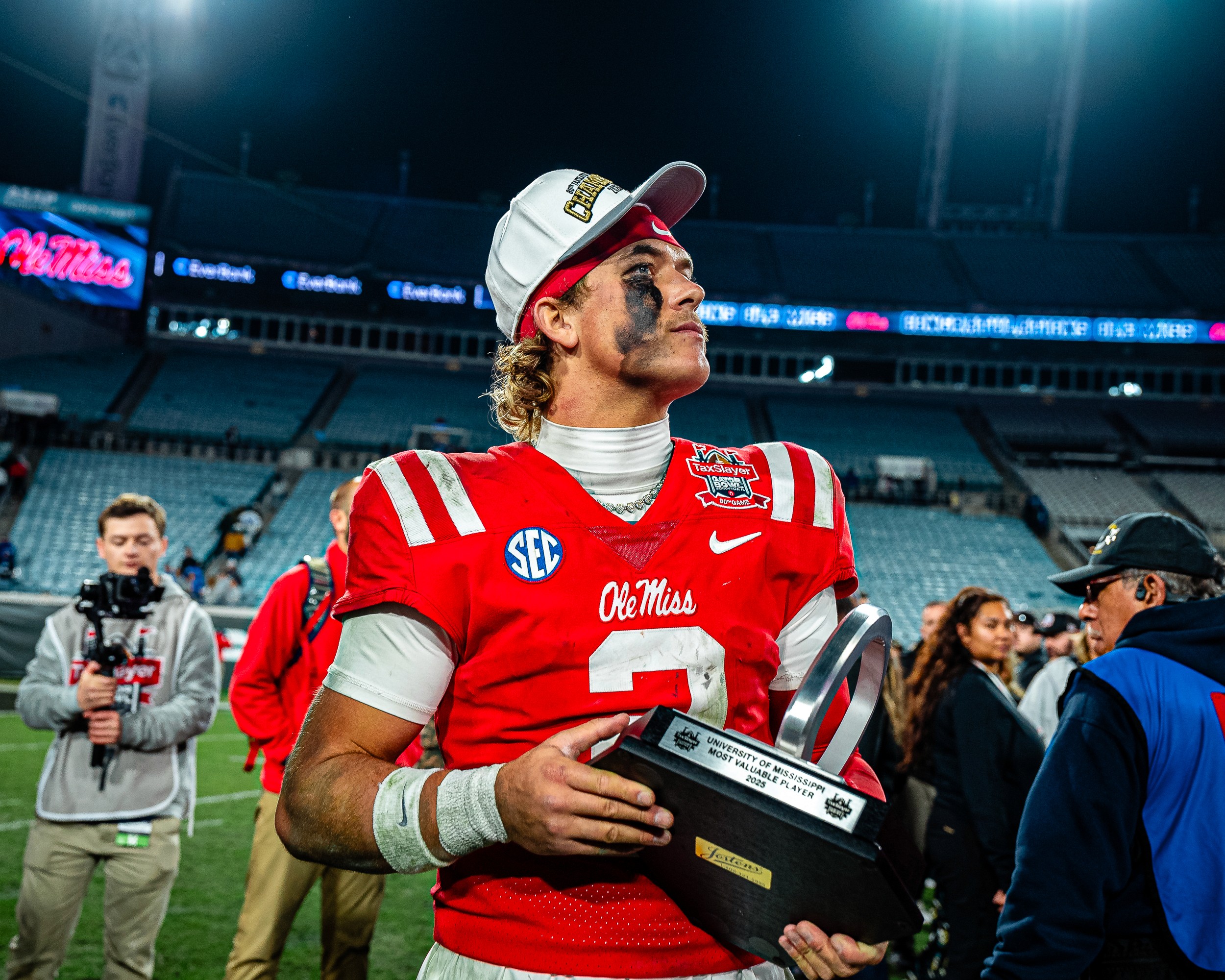 Jaxson Dart (2) with the Gator Bowl MVP trophy after the win, championship cap on, under the EverBank Stadium lights.