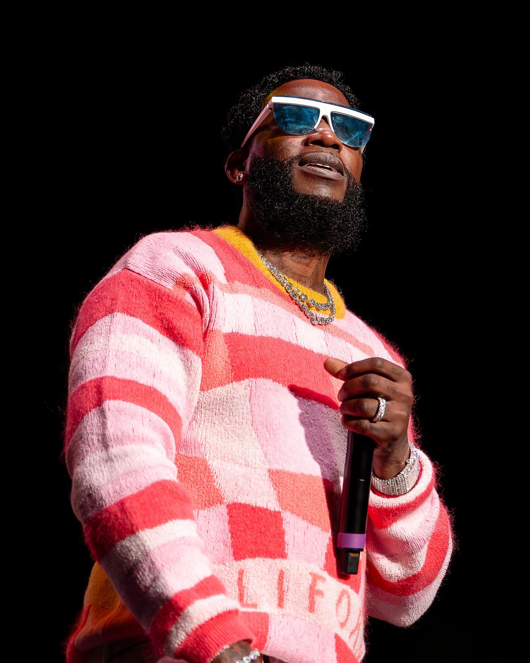 Gucci Mane in the checkered knit, shot from below the stage lip.