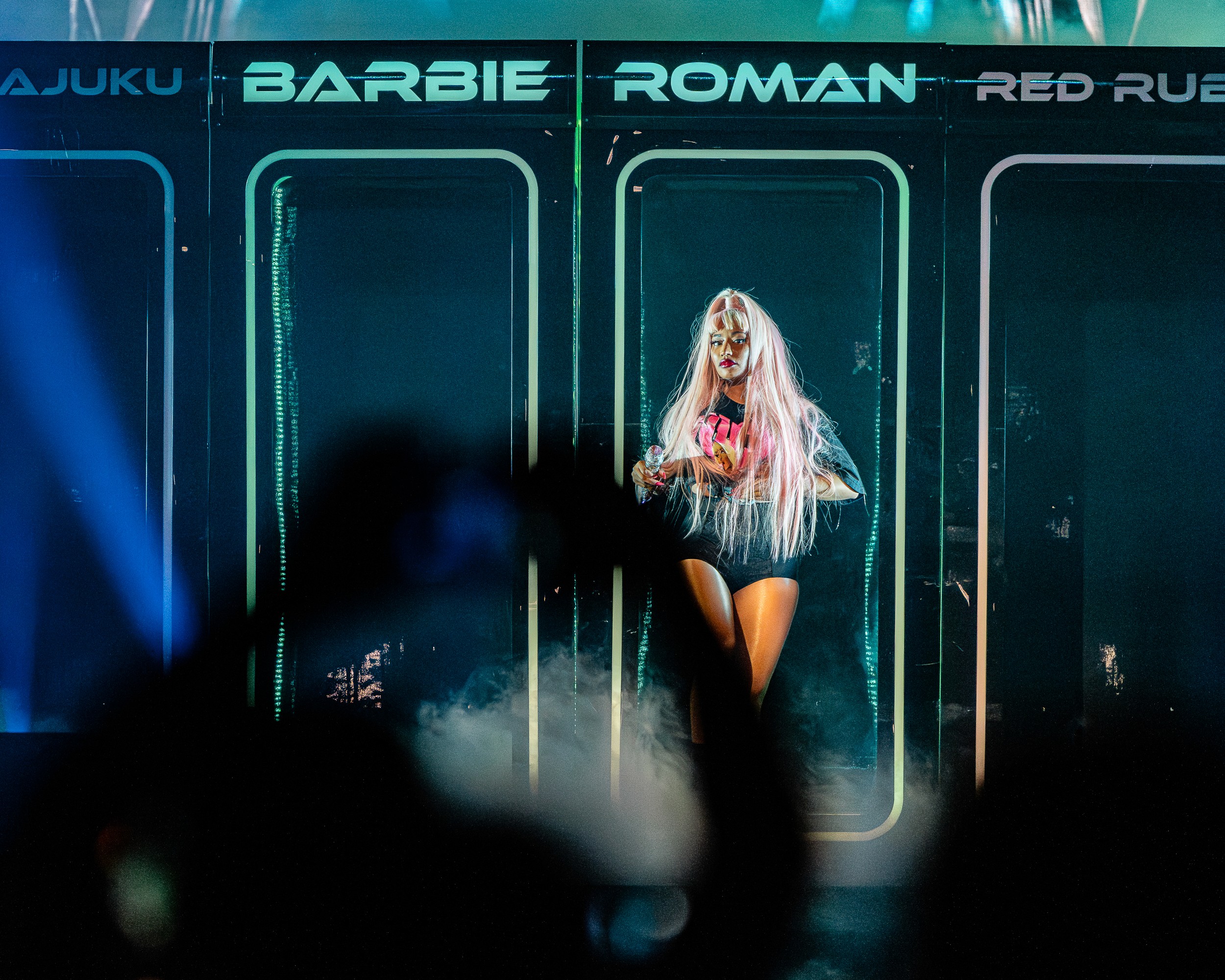 Under the BARBIE and ROMAN doors of the set, in long pink hair.