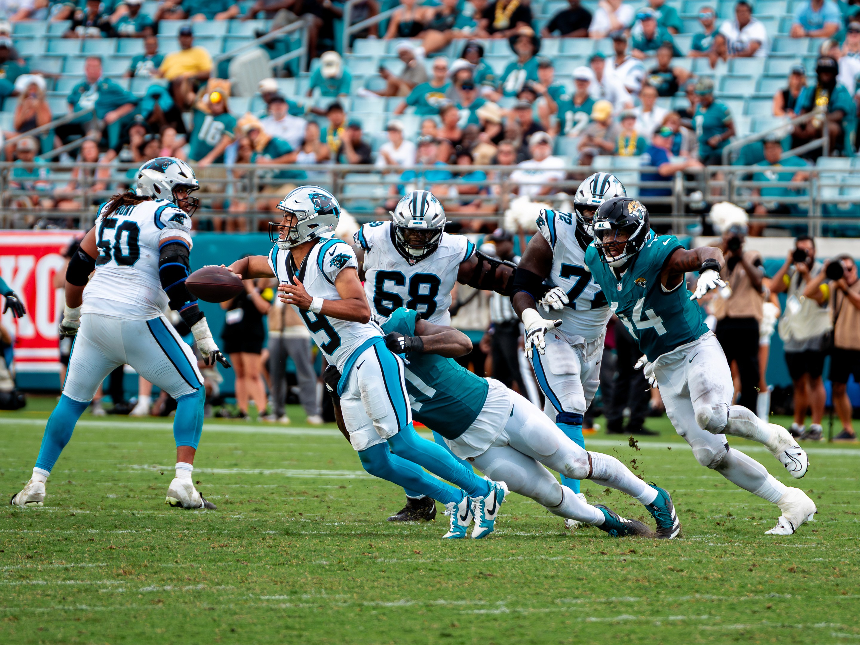 Panthers quarterback Bryce Young (9) is dragged down by a Jaguars rusher.