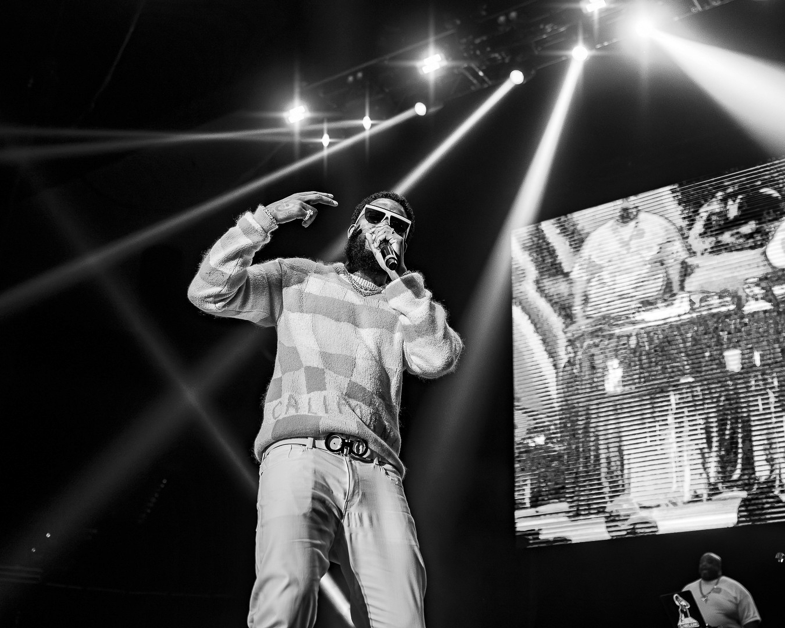 Gucci Mane on the mic in black and white, the light beams and the side screen behind him.
