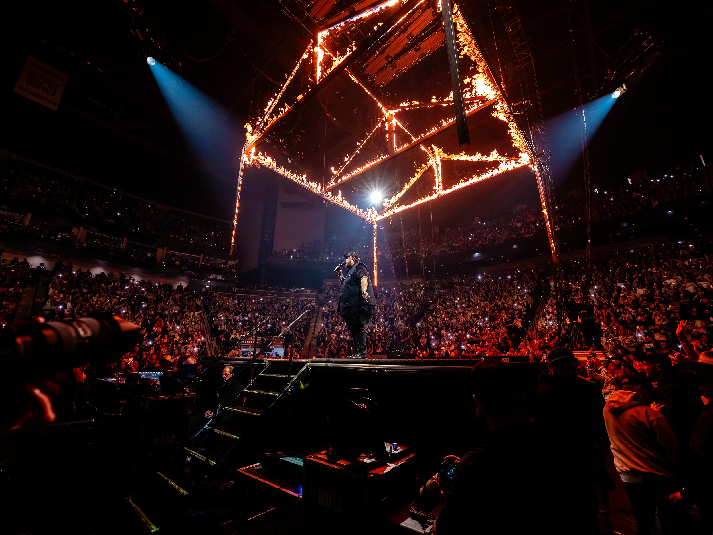 Jelly Roll alone on the B-stage under the burning rig, the whole arena lit by phones.