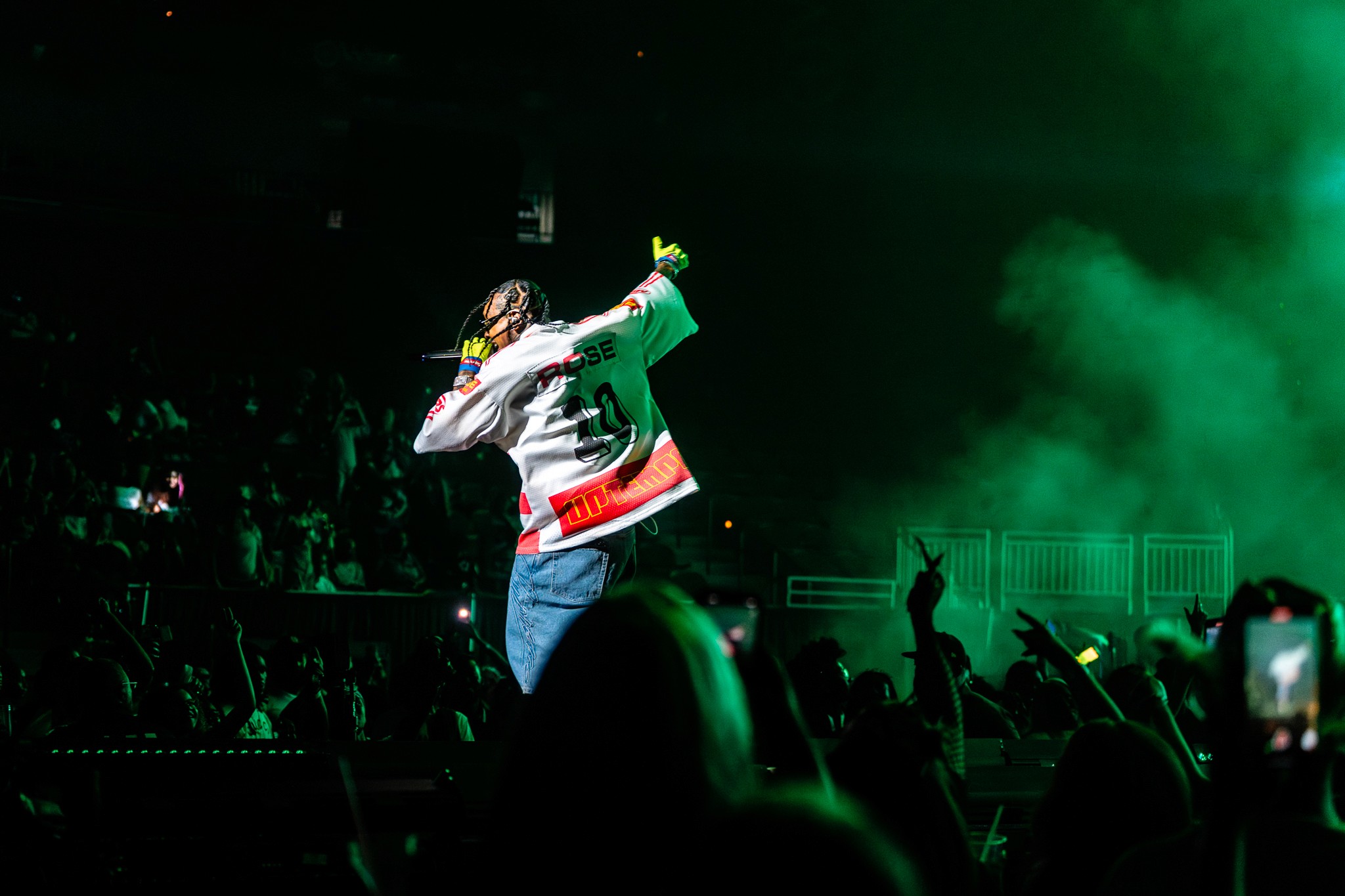 A supporting act with the crowd’s phones up under green light.