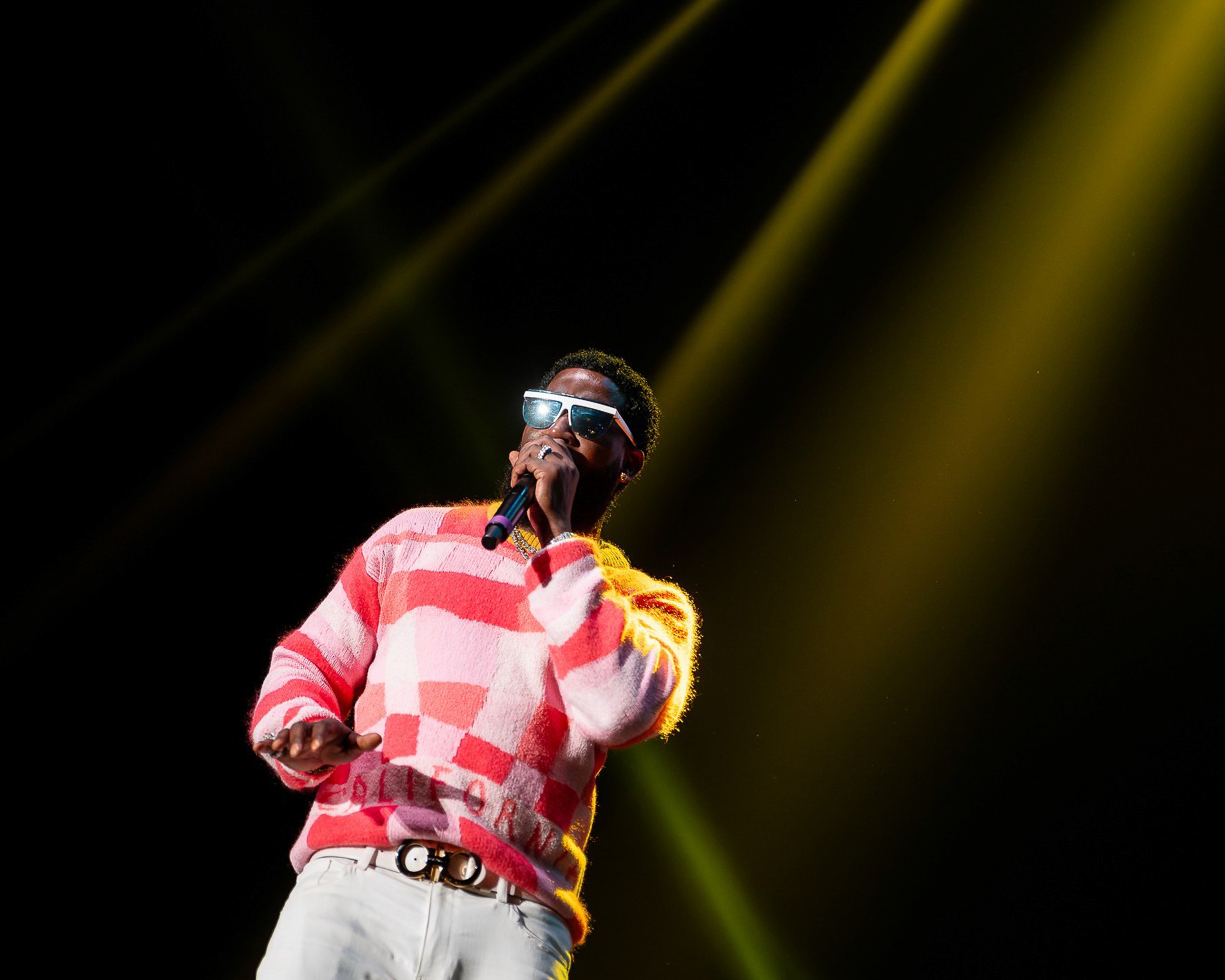 Gucci Mane under a gold beam, mic in hand.
