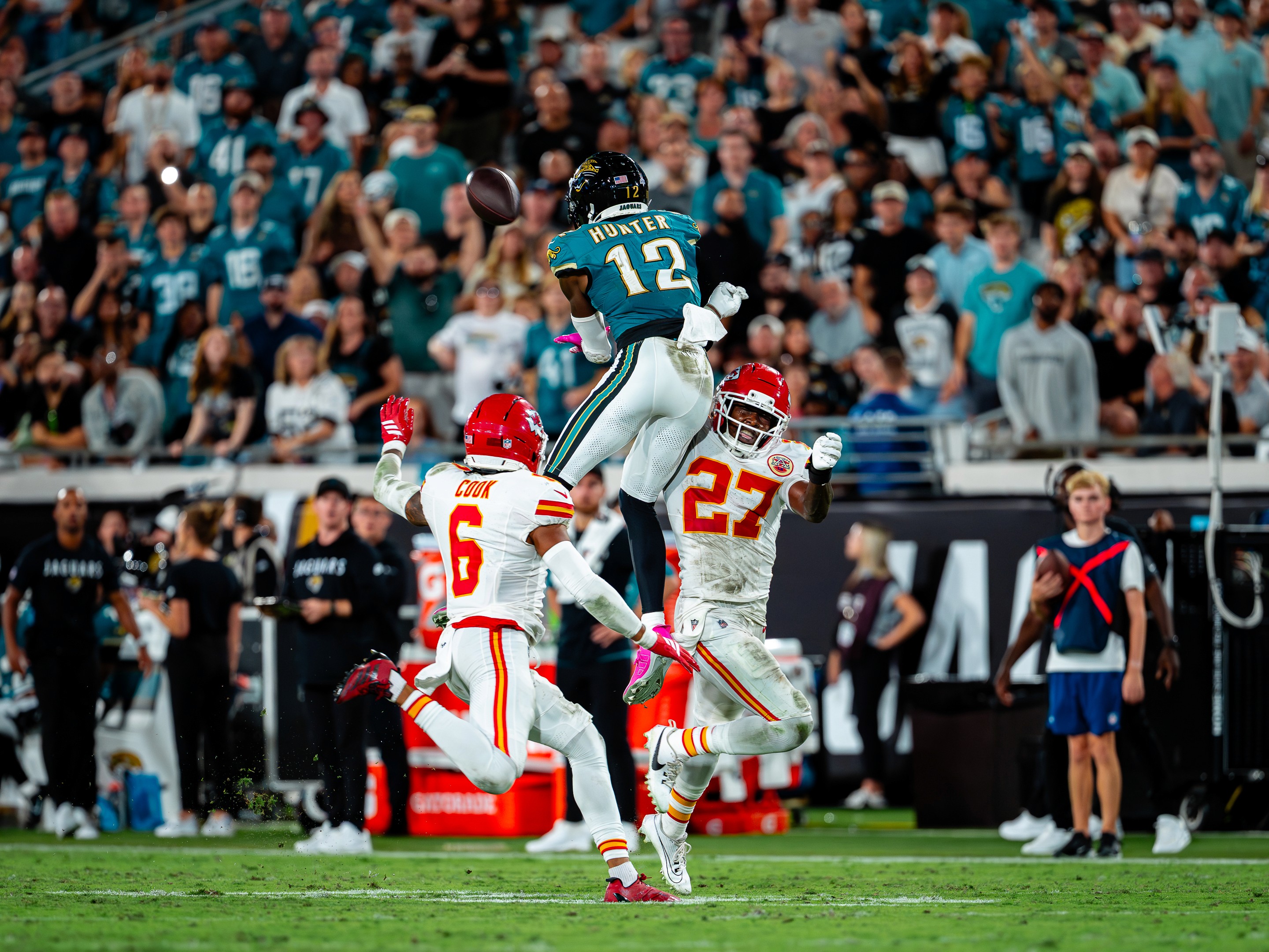 Travis Hunter (12) goes up for the ball between Chiefs defenders Bryan Cook (6) and Chamarri Conner (27).