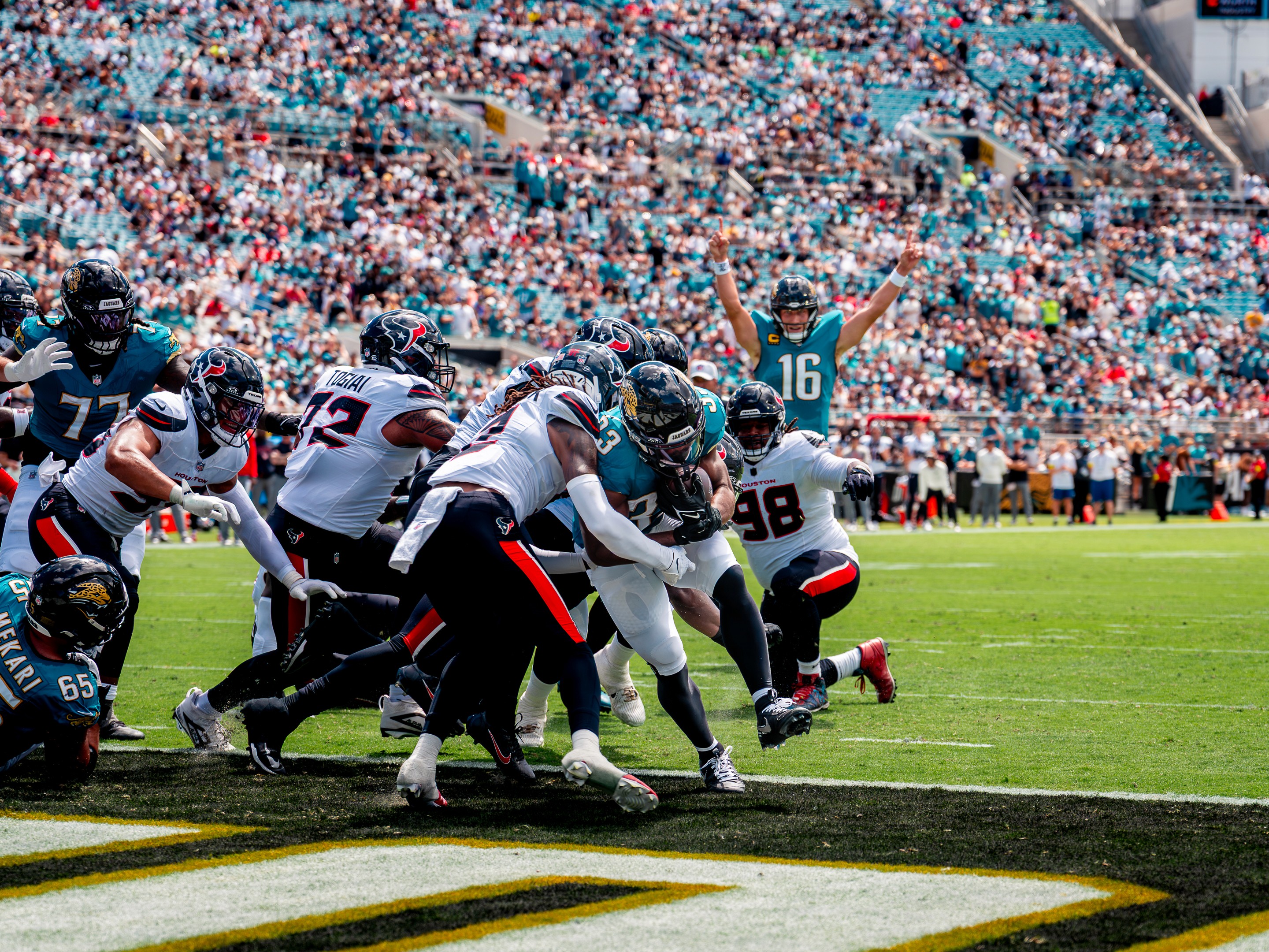 After the whistle, a Texans defender wraps up a Jaguars receiver (17) as the ball bounces free.