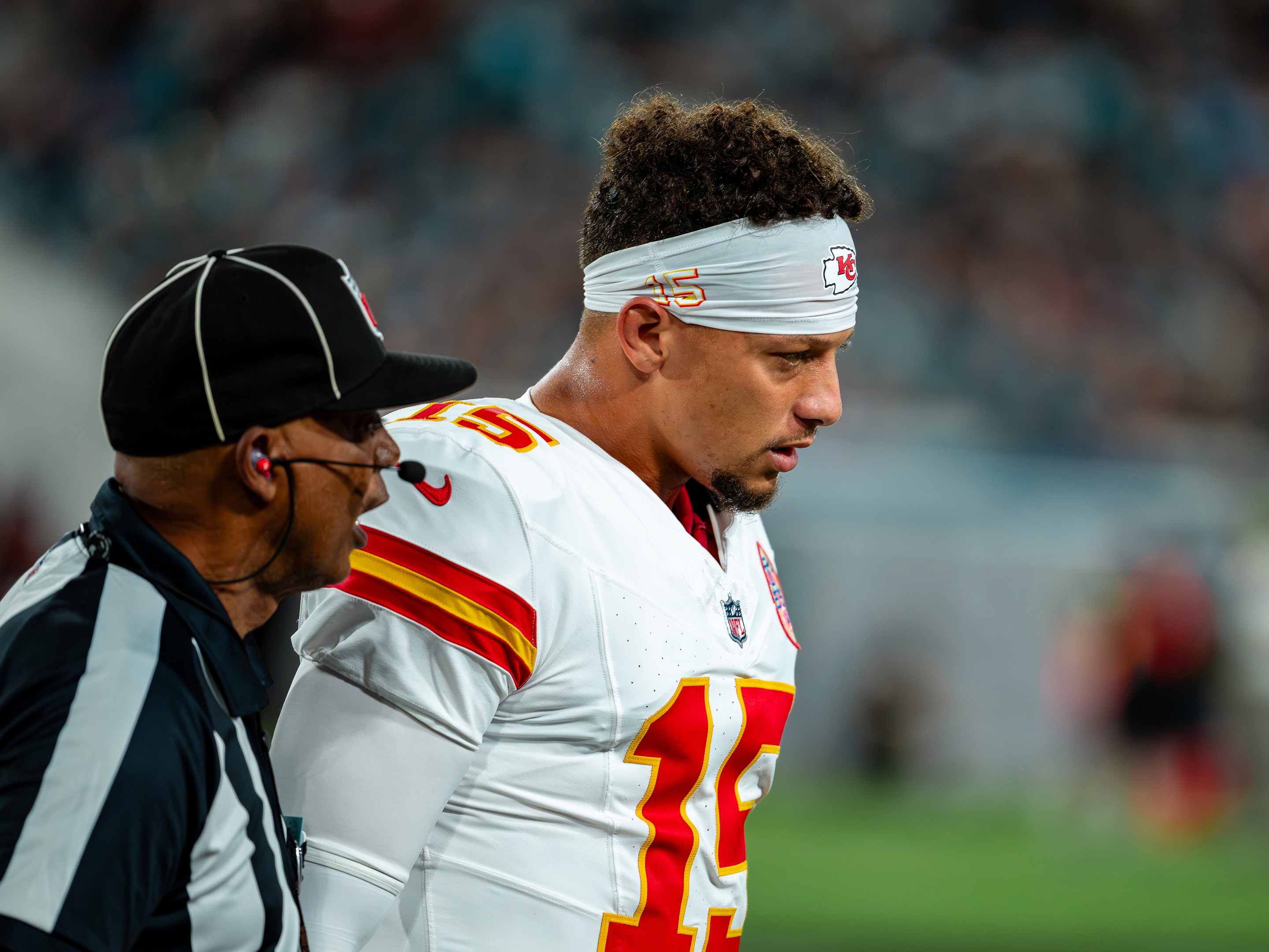 Patrick Mahomes beside an official on the sideline during a stoppage.