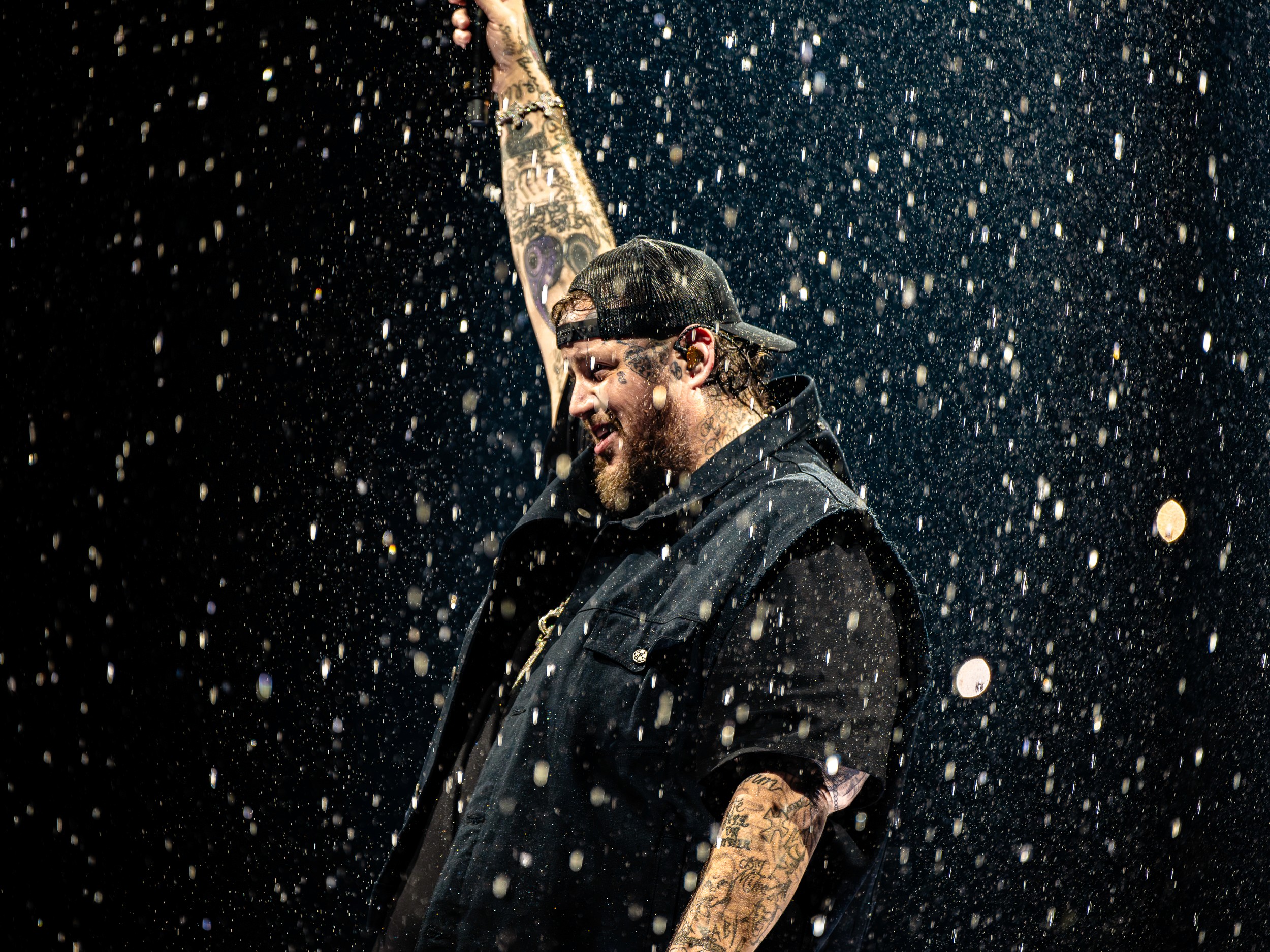 Sparks fall around Jelly Roll, arm raised, from the stage edge.