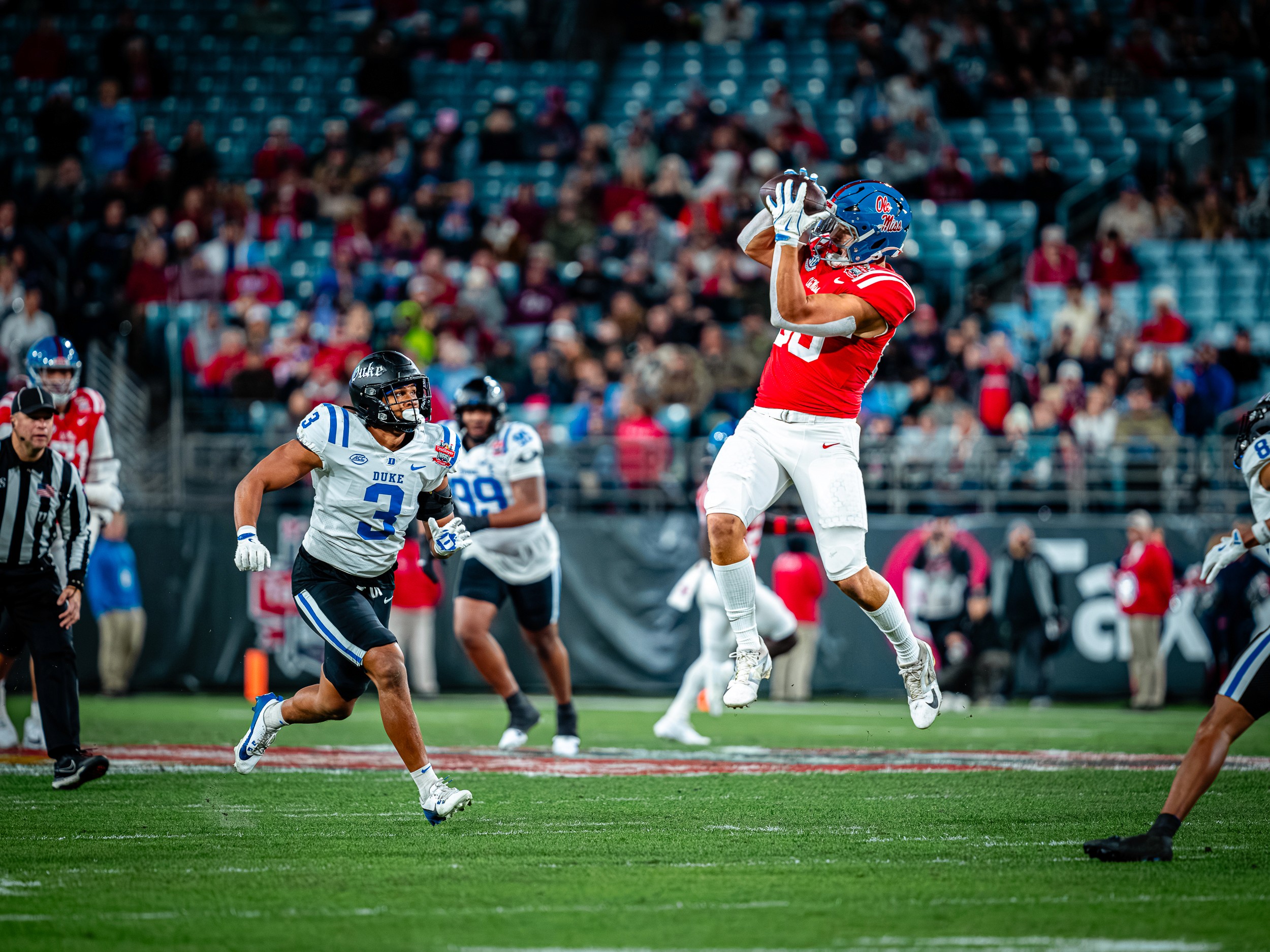 An Ole Miss receiver goes up for a catch in the middle of the field, Duke’s (3) closing.